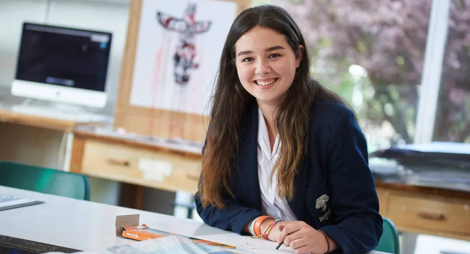 Una studentessa siede sorridente alla sua scrivania in un'aula della Bethany School.