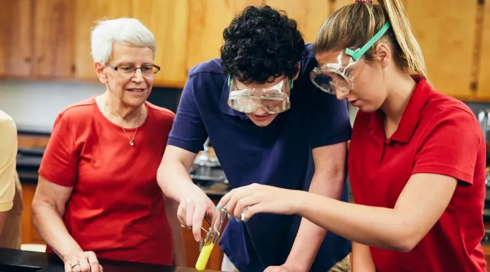 Tre studenti della Shalom Christian Academy lavorano insieme in una cucina con rivestimenti in legno.