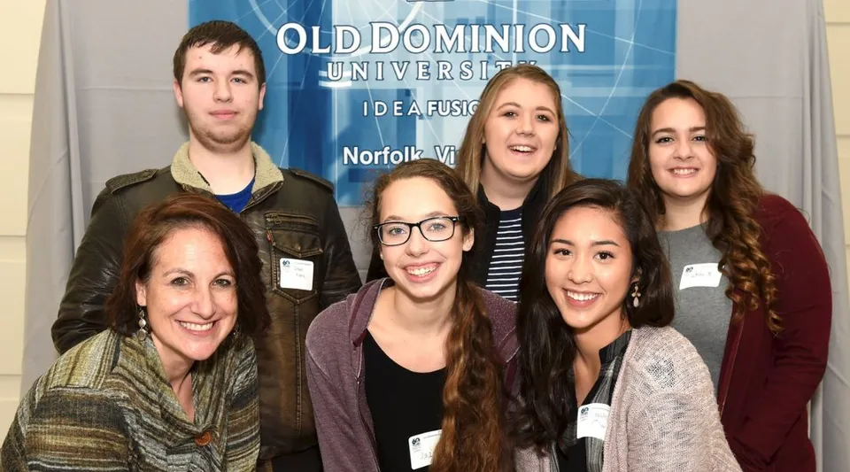 Un gruppo di studenti sorride davanti a uno striscione della Old Dominion University nel campus della Atlantic Shores Christian School.