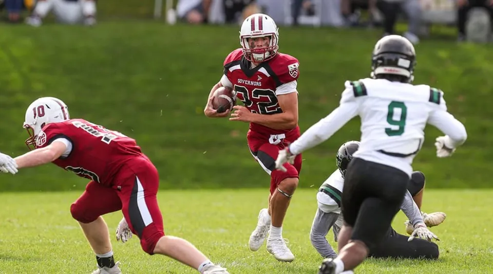 Un giocatore di football americano di The Governor's Academy corre con la palla sul campo da gioco.