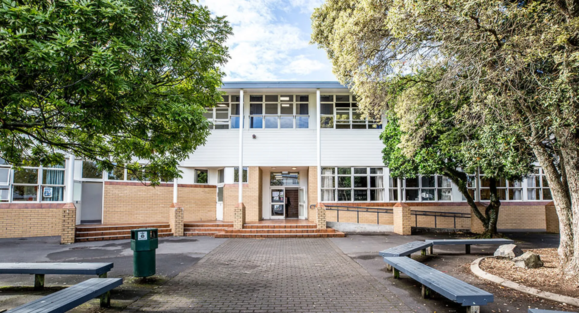 L'edificio in mattoni a due piani con grandi finestre e ingresso coperto si trova nel campus della Mount Roskill Grammar.