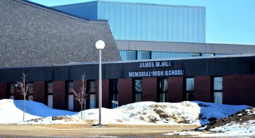 Il grande edificio della James M. Hill Memorial High School sorge su un terreno coperto di neve.