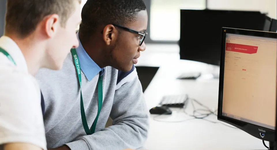 Due persone al computer nel campus della Theale Green School concentrate sullo schermo.