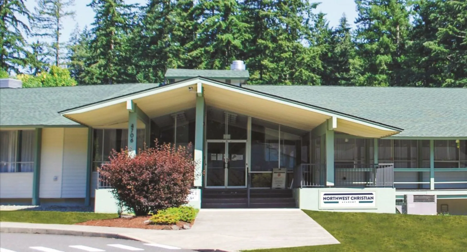 Il moderno edificio scolastico ad un piano della Northwest Christian High School è circondato da un'area boschiva.
