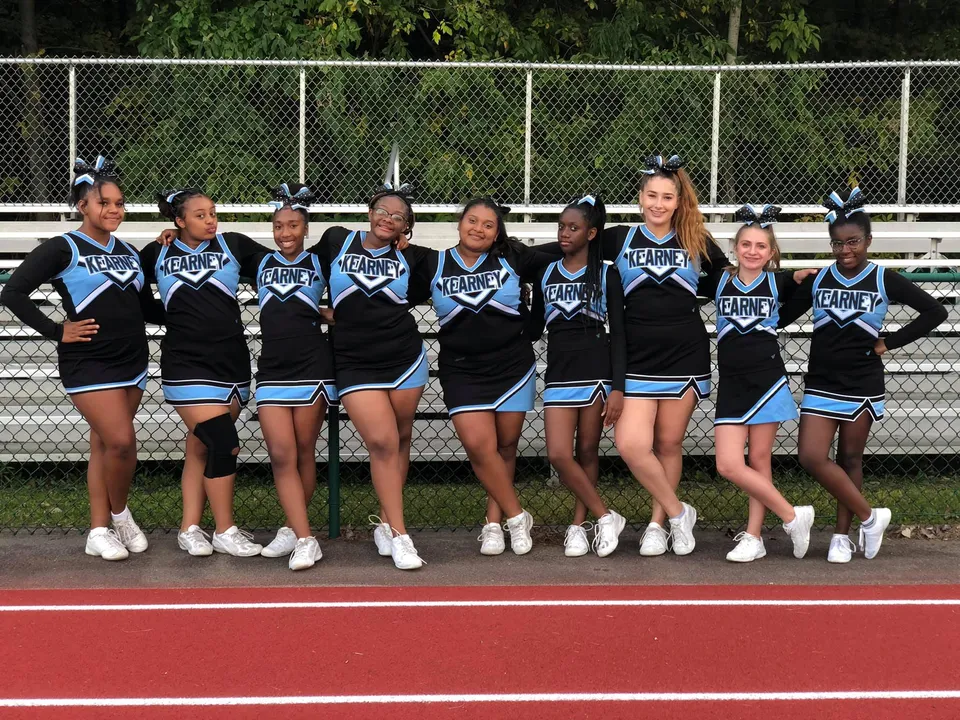 Un gruppo di cheerleader in divisa si trova sul campo sportivo della Bishop Kearney High School.