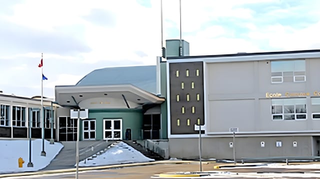 L'edificio moderno della École Camrose Composite High School con un'architettura d'impatto e un piazzale pavimentato sotto un cielo nuvoloso.
