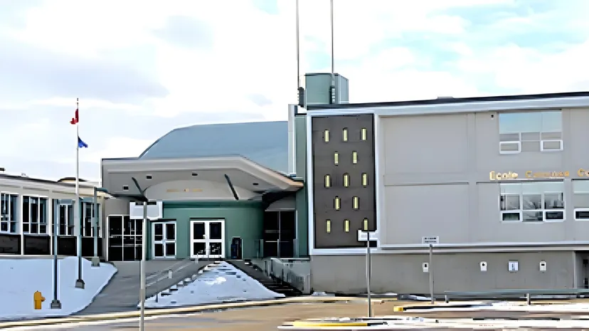 L'edificio moderno della École Camrose Composite High School con un'architettura d'impatto e un piazzale pavimentato sotto un cielo nuvoloso.