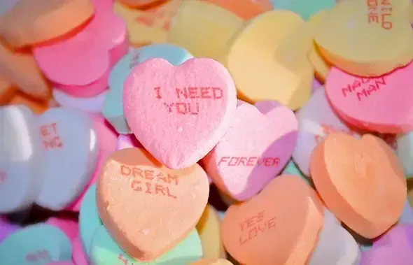 Caramelos de colores pastel con forma de corazón y mensajes impresos en inglés