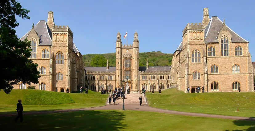 L'edificio principale in stile gotico del Malvern College è circondato da un grande prato verde e si trova sotto un cielo azzurro limpido.