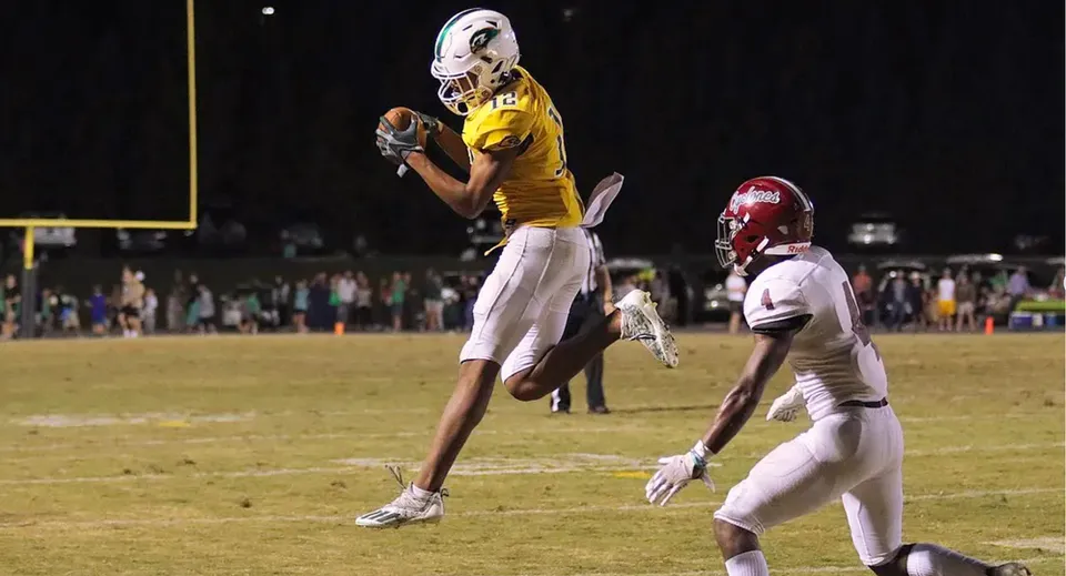 Un giocatore di football americano della Ben Lippen School afferra la palla al volo durante una partita in notturna.