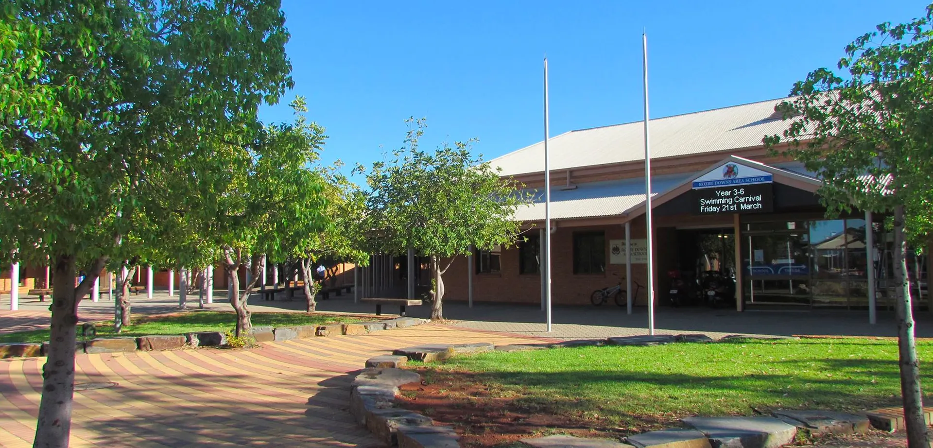L'edificio d'ingresso moderno della Roxby Downs Area School è circondato da piante verdi e da un vialetto lastricato.