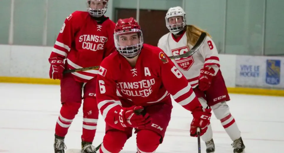 Un gruppo di giocatori di hockey in uniformi rosse e bianche sul ghiaccio dello Stanstead College.