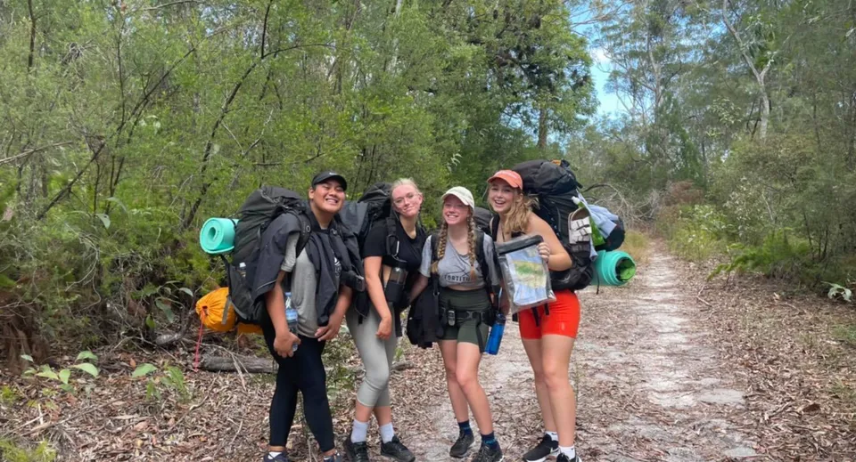 Gli studenti della Nerang State High School camminano con gli zaini lungo un sentiero naturale.