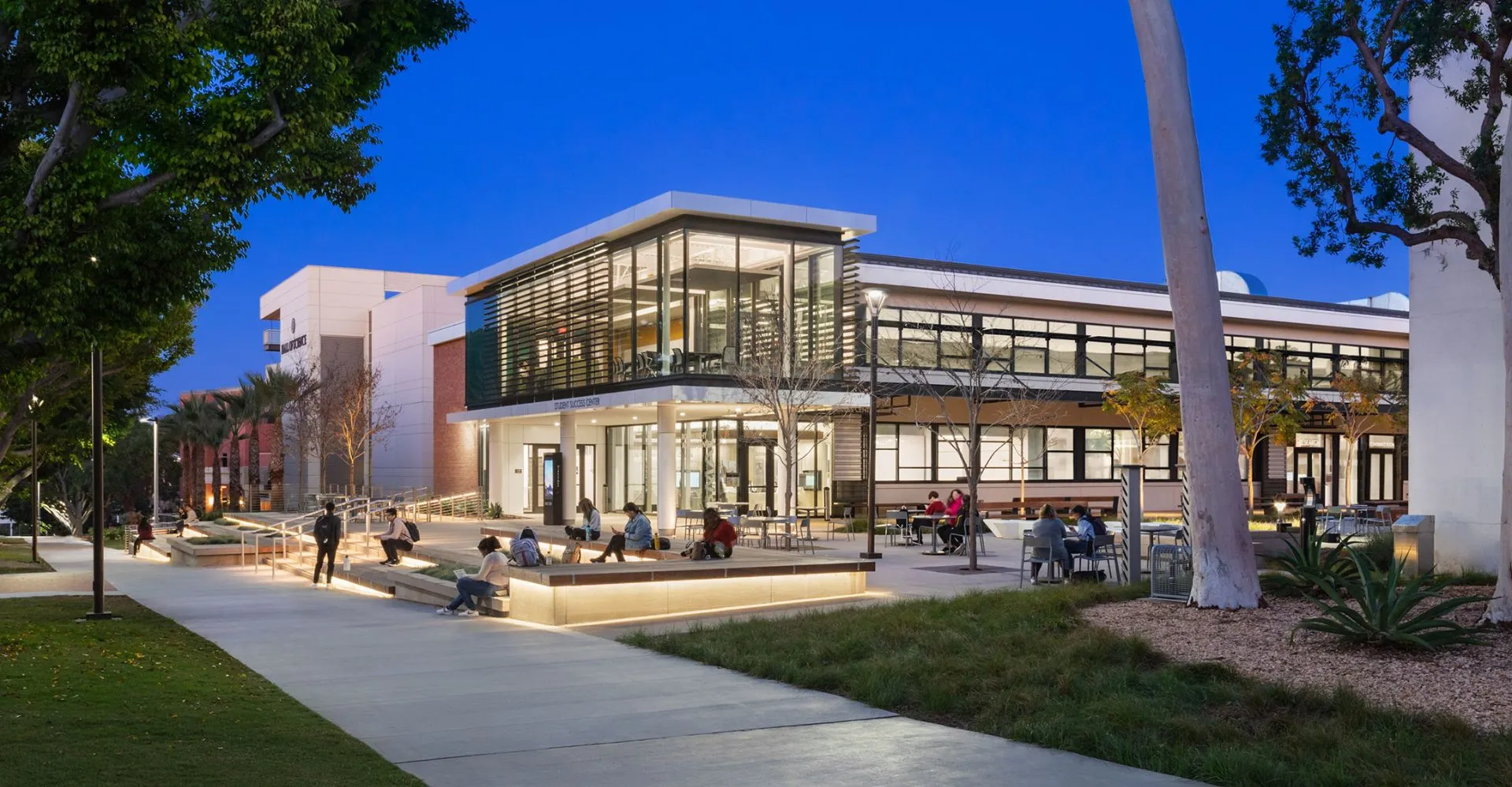 L'edificio moderno in vetro con un'area per sedersi nel campus della California State University Long Beach sotto un cielo limpido.