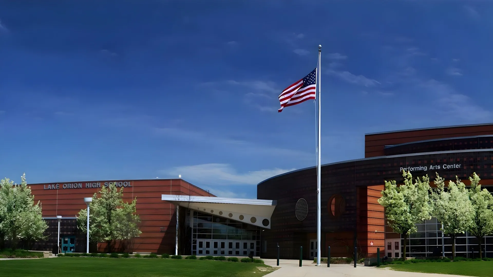 Eine große amerikanische Flagge weht auf dem Dach eines modernen Backsteingebäudes auf dem Campus des F-1 No Choice Programm USA.
