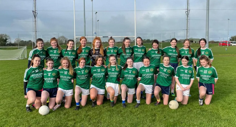Un gruppo di giovani calciatrici in maglia verde in posa sul campo da calcio del Castleblayney College.