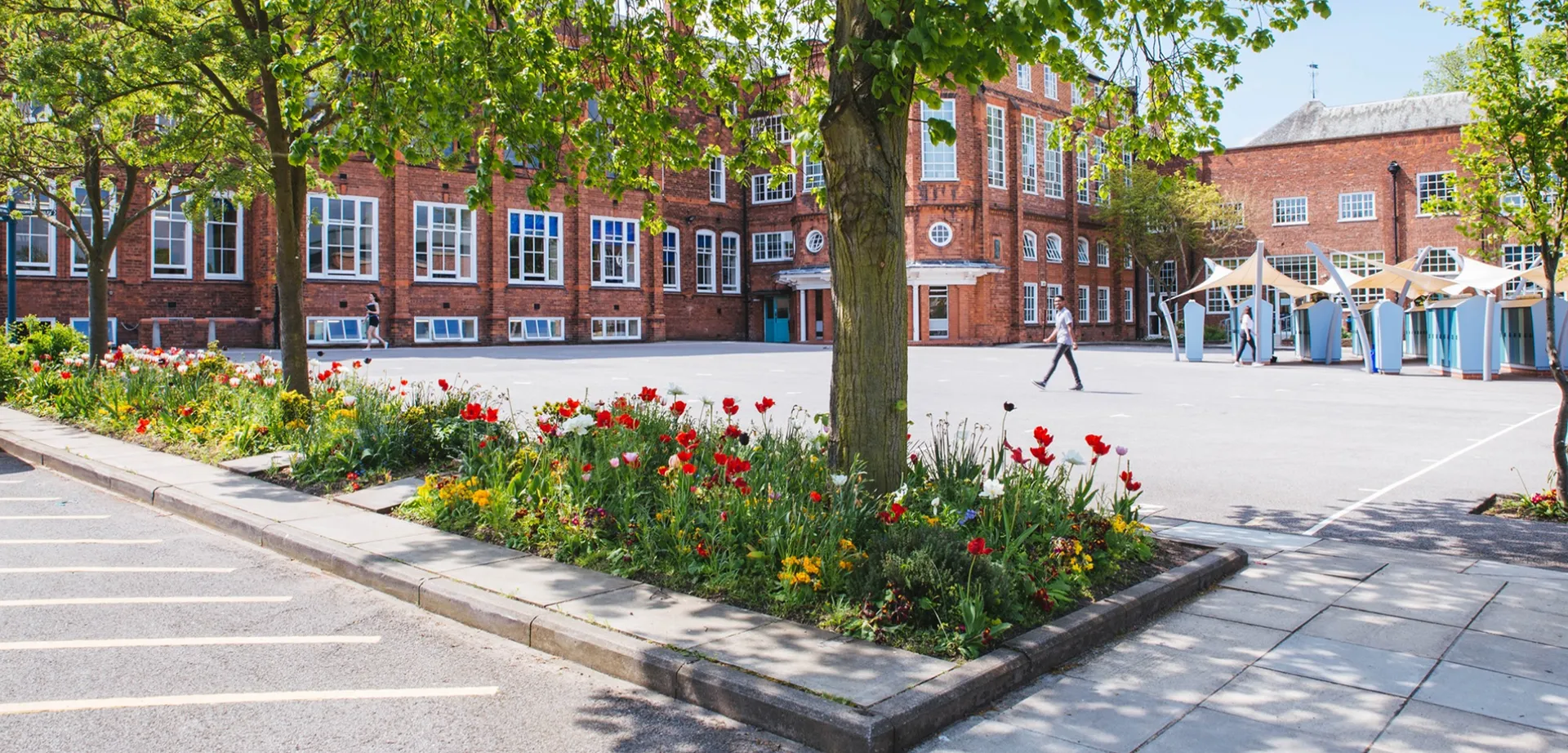L'edificio della Bootham School si intravede dietro un vialetto con tulipani colorati e una fitta chioma di alberi.