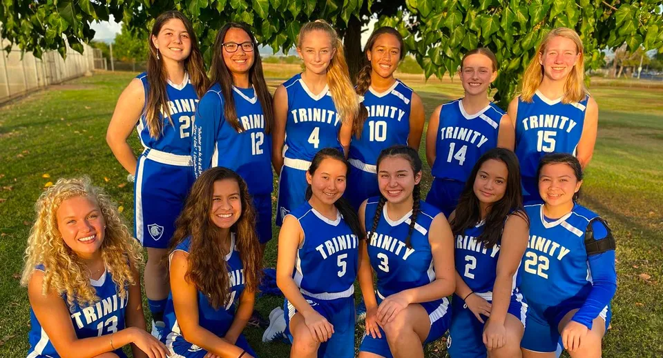 Un gruppo di giovani studentesse in divisa sportiva blu posa all'aperto nel campus della Trinity Christian School.
