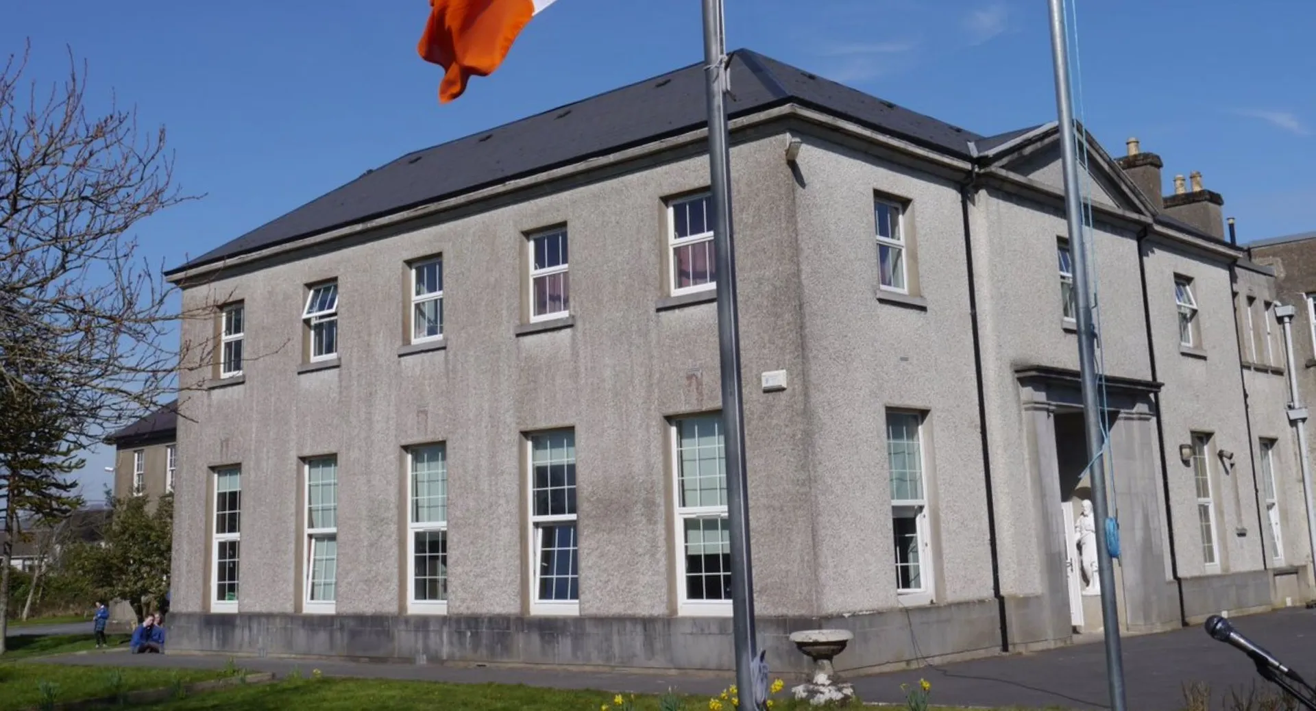 L'edificio a più piani della St. Joseph’s Secondary School a Castlebar con una bandiera arancione davanti a un cielo blu.
