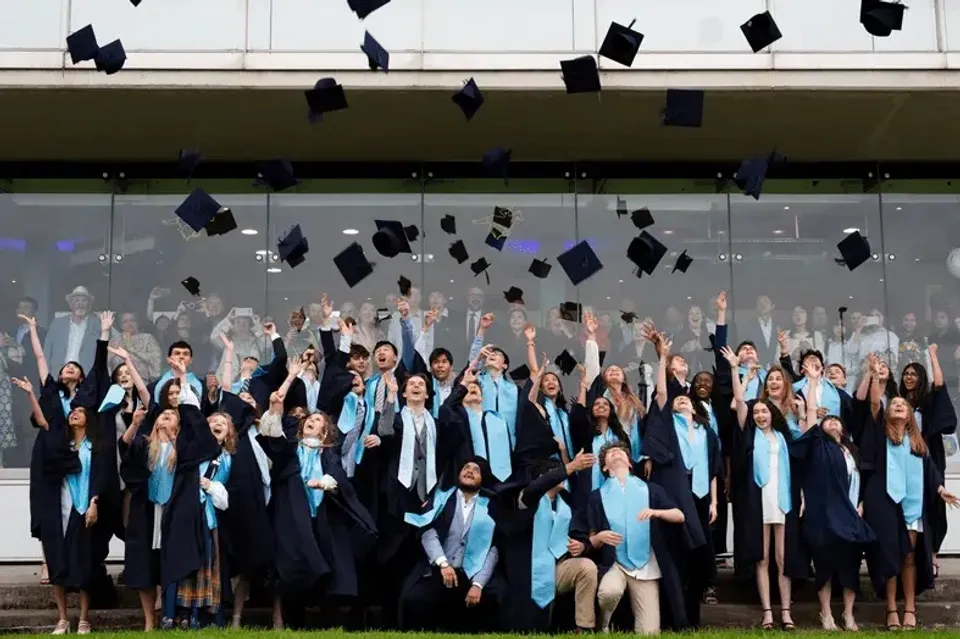 Studenti della Nord Anglia International School Dublin lanciano in aria i tocchi indossando toghe da diploma.