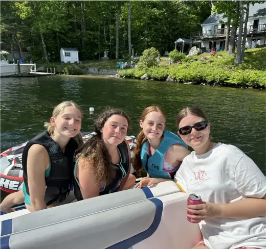 Quattro ragazze sorridono su una barca su un lago circondato dal bosco negli Stati Uniti
