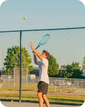 Leo serve la pallina durante una partita di tennis su un campo all'aperto negli Stati Uniti.