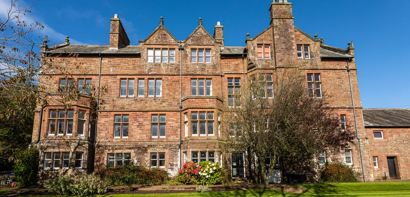 L'edificio storico in mattoni della St. Bees School è circondato da alberi e tanto verde.
