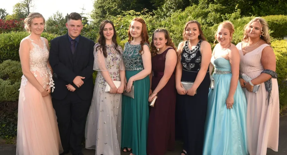 Un gruppo di persone vestite in modo elegante posa all'aperto nel campus della St. Felix School.