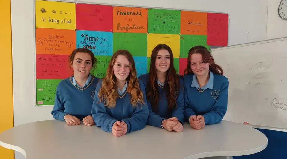 Quattro studentesse della Kinsale Community School siedono a un tavolo in un'aula colorata.