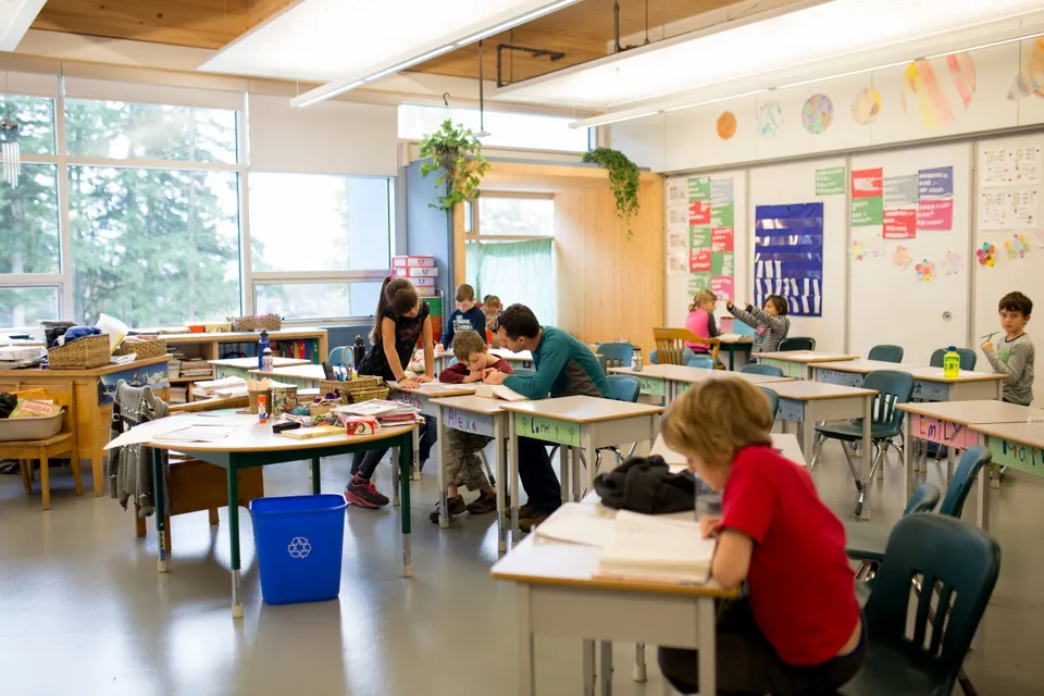 Gli studenti della École des Deux-Rives sono in un'aula vivace impegnati in varie attività, circondati da materiali didattici.