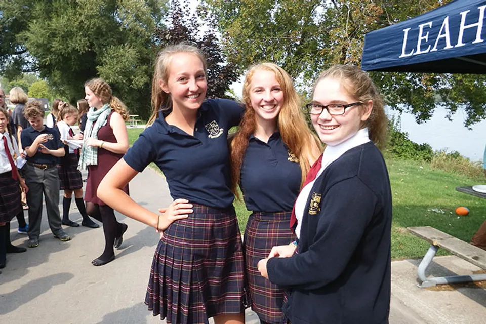 Tre studentesse del Leahurst College in divisa scolastica sorridono insieme all'aperto.