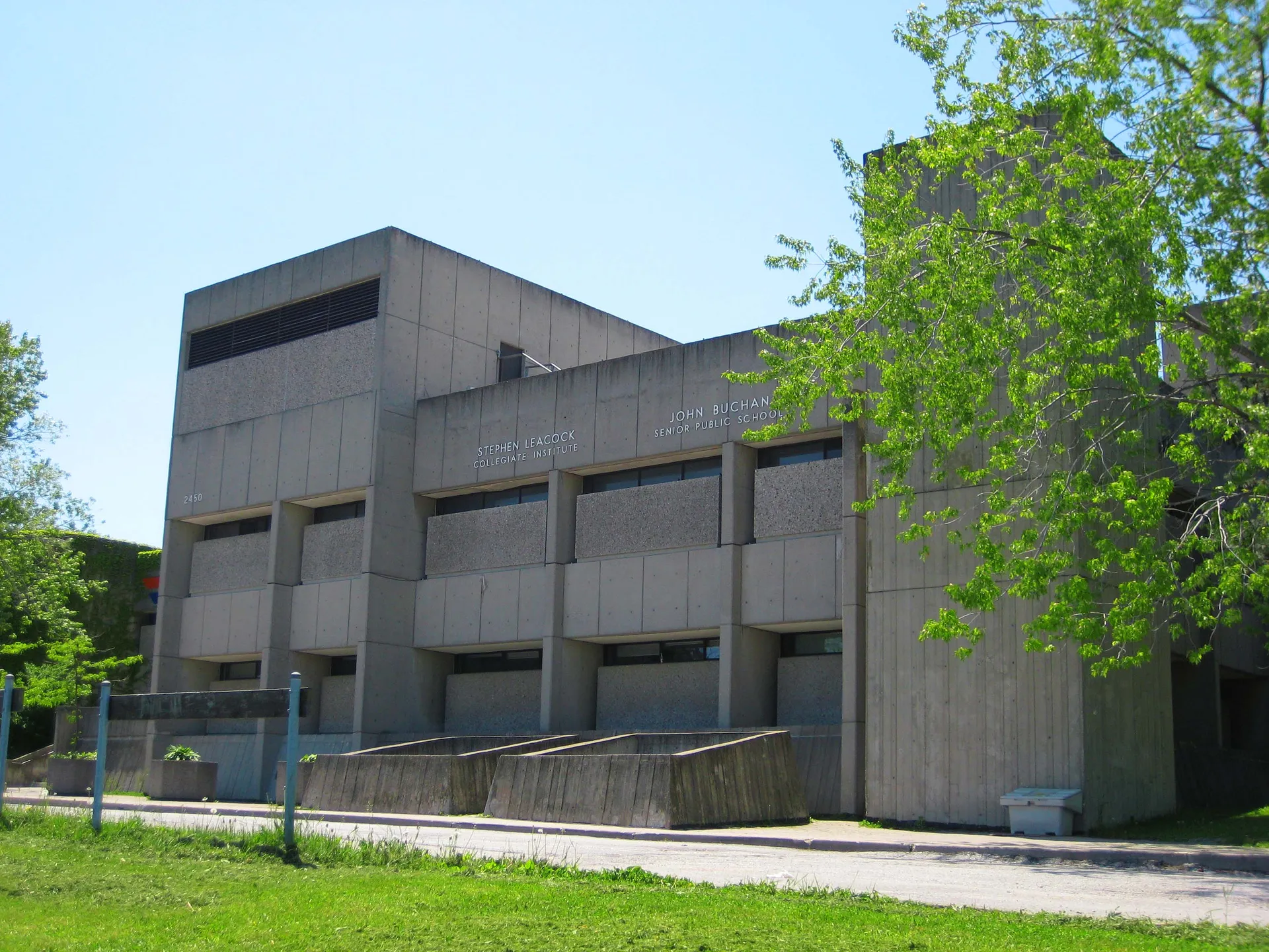 L'edificio scolastico moderno del Stephen Leacock Collegiate Institute, con grandi finestre e un ingresso caratteristico, è circondato da alberi verdi.