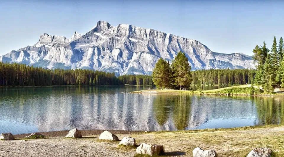 Un lago riflette una catena montuosa rocciosa e foreste di pini vicine alla Heritage Christian Academy.