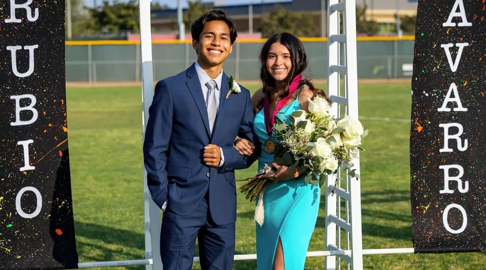 Una coppia davanti a uno sfondo con la scritta Rubio nel campus della Valley Christian High School.