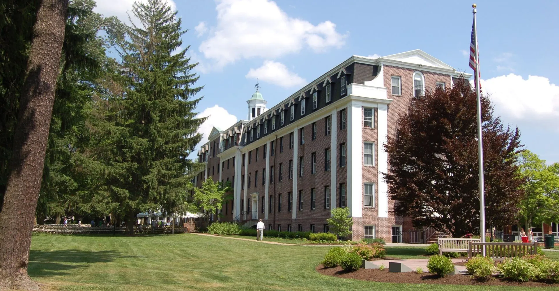 Il grande edificio in mattoni con torre nel campus della The Pennington School è circondato da prati e alberi.
