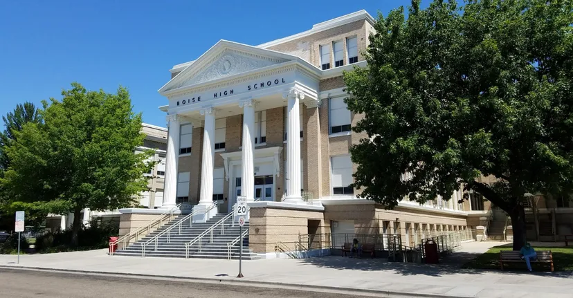 L'edificio del Boise School District si erge con colonne bianche circondato da alberi verdi in una giornata di sole.