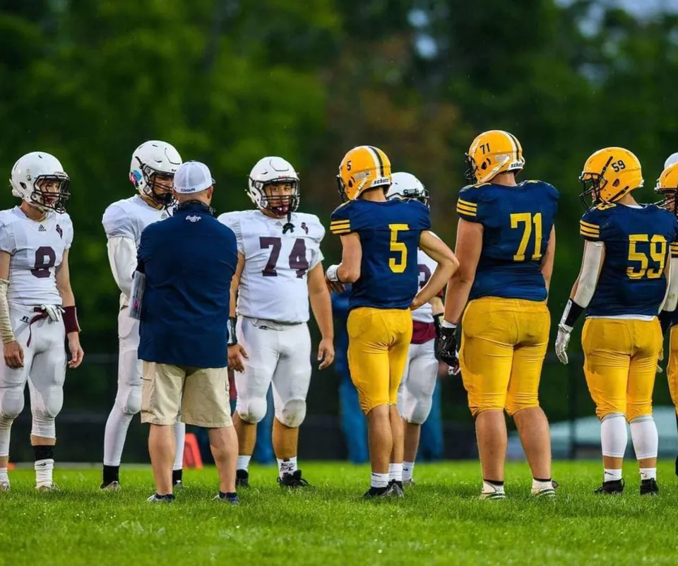 Un gruppo di giocatori di calcio si trova insieme su un campo da gioco all'aperto della Mount Blue High School.