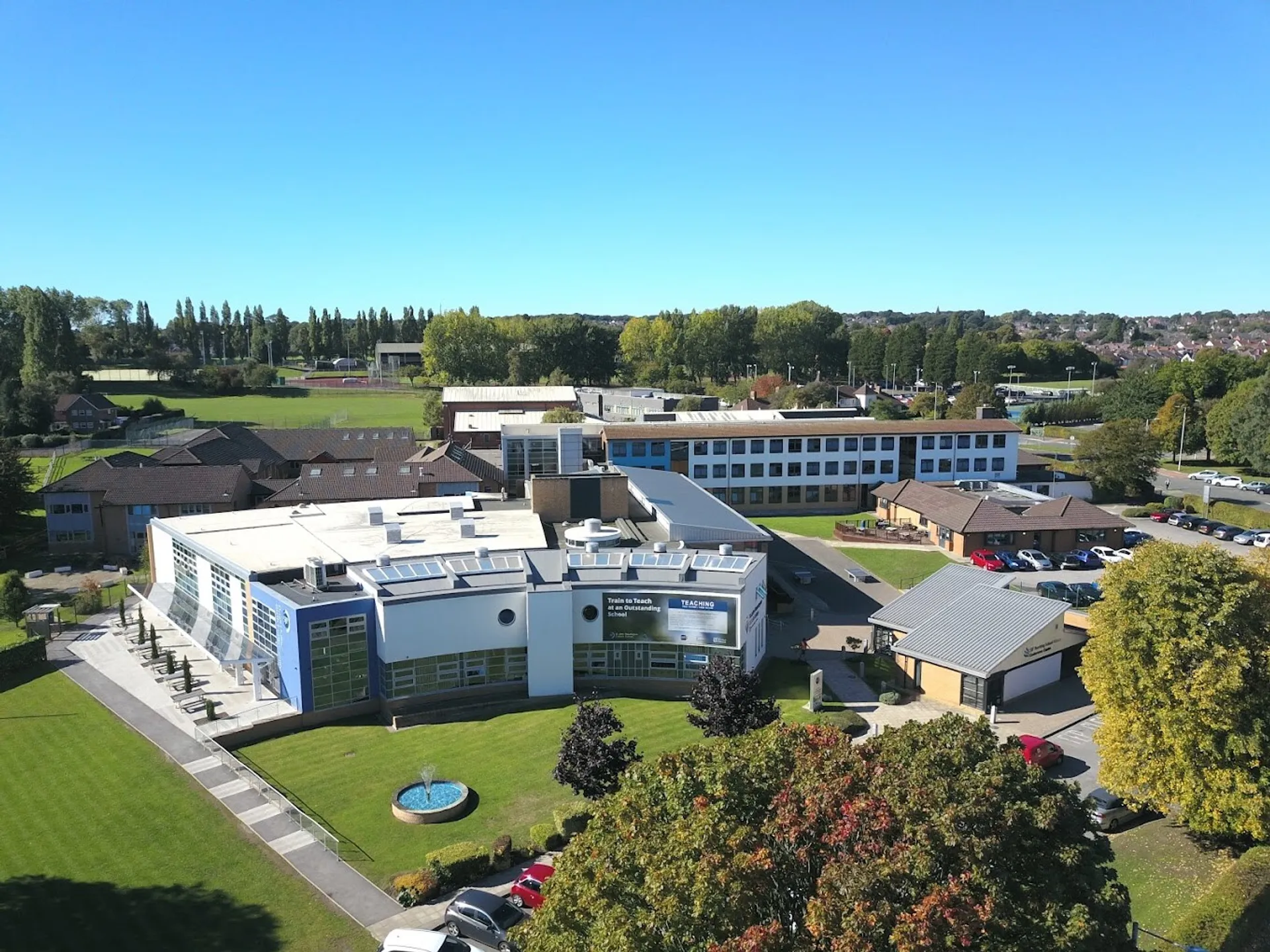 L'ampio campus del St. John Plessington Catholic College con edifici moderni e uno spazio verde sotto un cielo limpido.