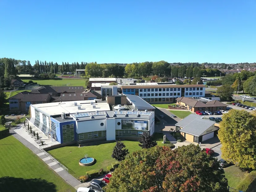 L'ampio campus del St. John Plessington Catholic College con edifici moderni e uno spazio verde sotto un cielo limpido.