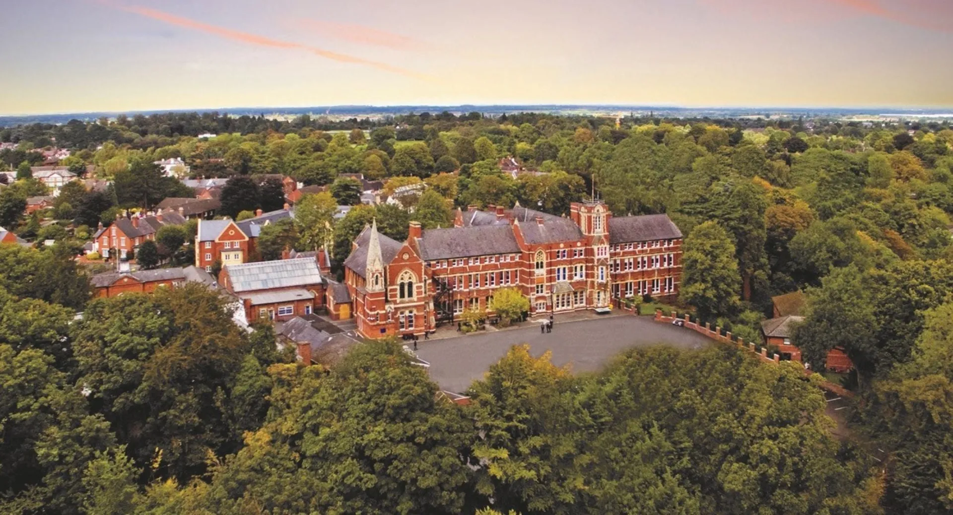 Vista aerea del campus storico del Tettenhall College con edifici in mattoni rossi e dintorni verdi al tramonto.