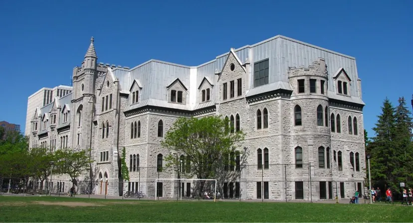 L'edificio storico in pietra del Lisgar Collegiate Institute con torri e un campo sportivo in primo piano.