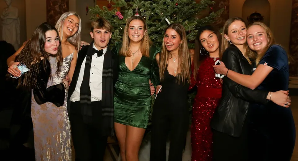 Studenti della Stephen Perse Foundation posano davanti a un albero decorato durante la festa di Natale.