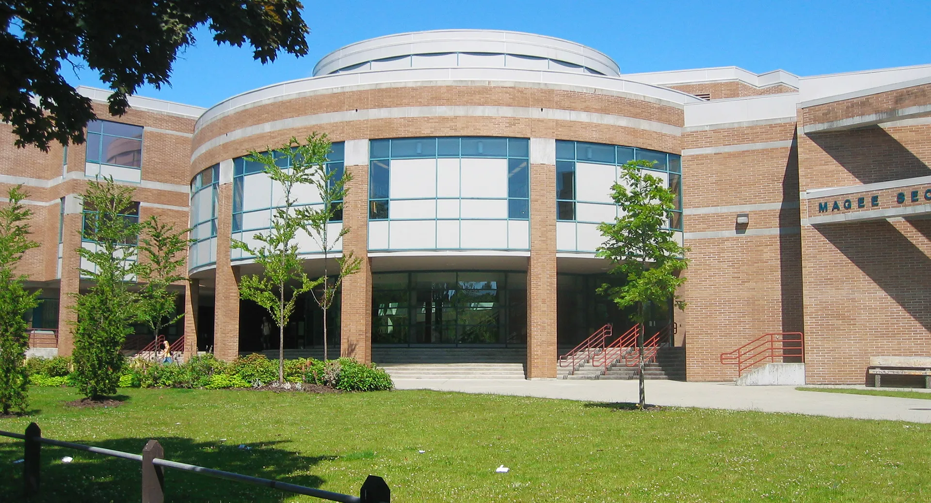 L'edificio in mattoni della Magee Secondary School con un ingresso centrale rotondo in vetro e un prato antistante.