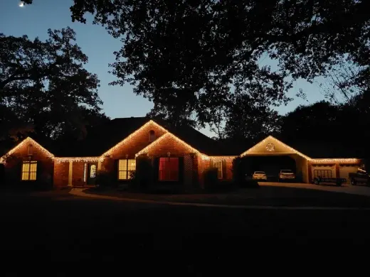 Casa de una familia anfitriona al anochecer con luces cálidas en el tejado