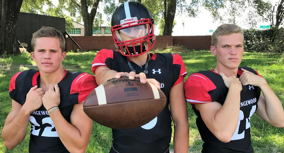 Tre studenti della Orangewood Christian School in divisa sportiva con un pallone da football in un'area simile a un parco.