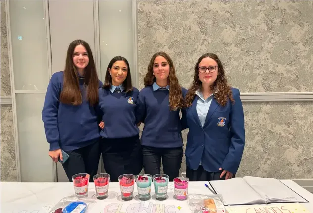 Quattro studentesse in divisa dietro un banco con candele fatte a mano in Irlanda