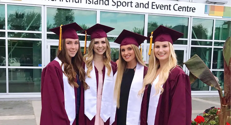 Quattro studentesse della NorKam Secondary School con la toga da diploma davanti al Whidbey Island Sport and Event Centre.