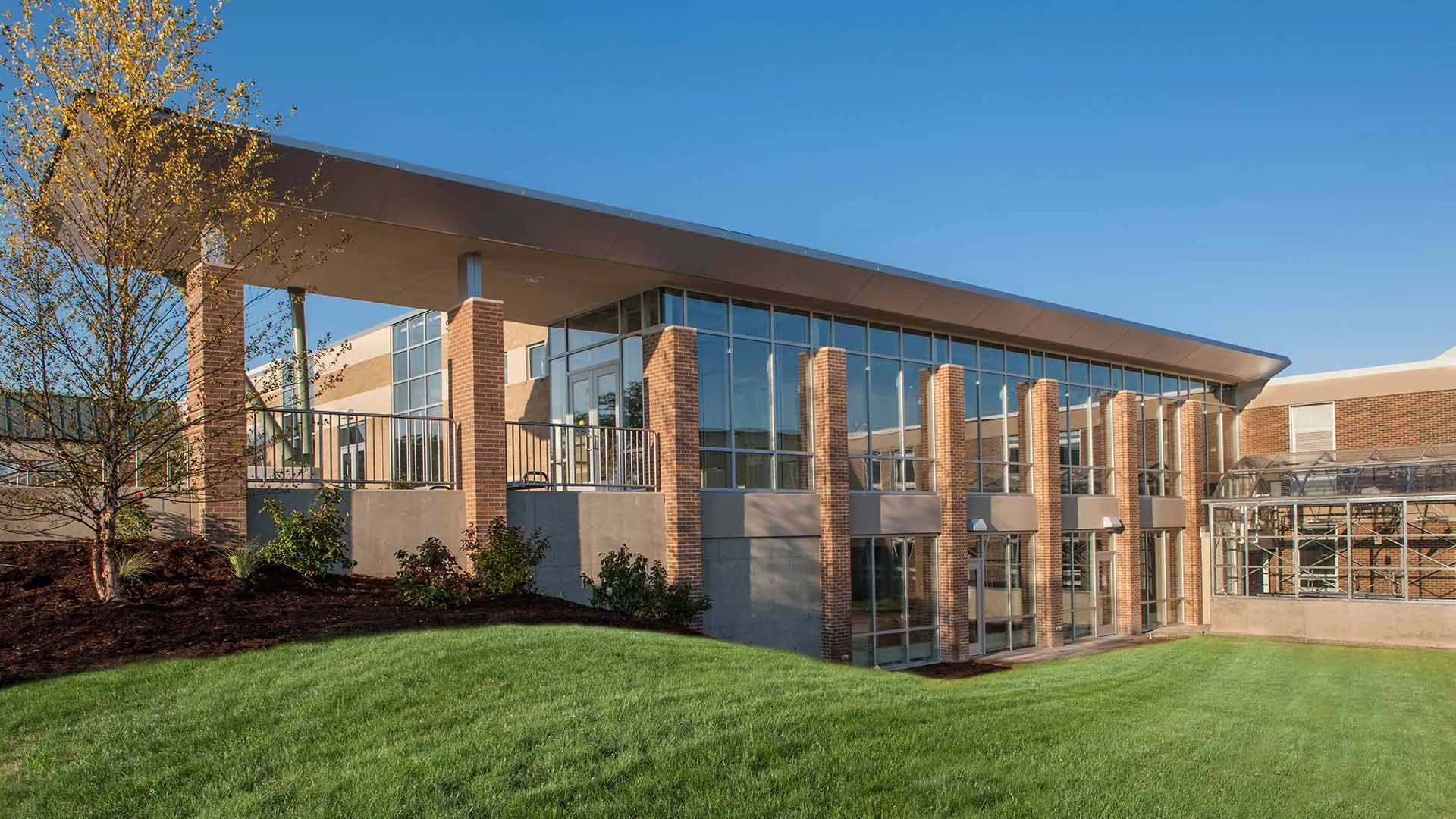 L'edificio moderno a più piani della Grand Rapids Christian High School, con la sua facciata in vetro, sorge su un'area verde sotto un cielo limpido.