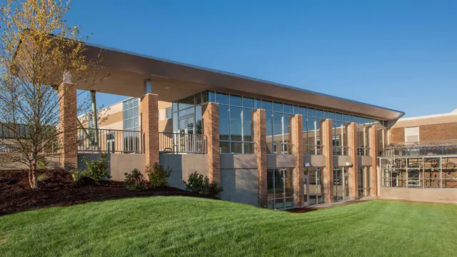 L'edificio moderno a più piani della Grand Rapids Christian High School, con la sua facciata in vetro, sorge su un'area verde sotto un cielo limpido.
