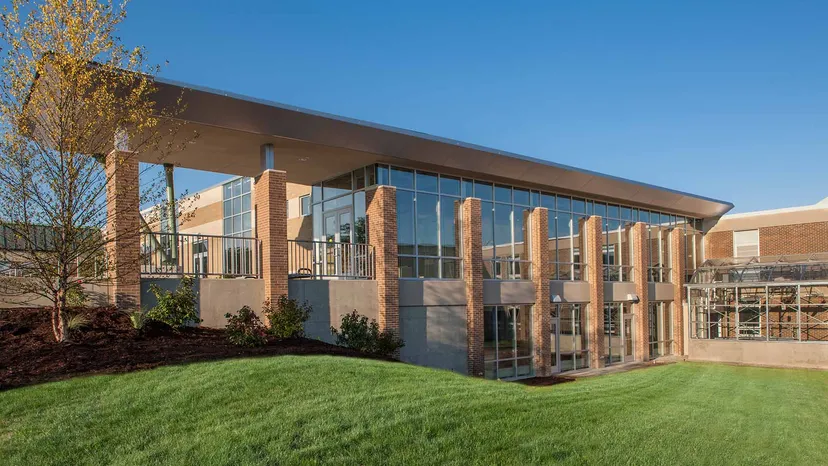 L'edificio moderno a più piani della Grand Rapids Christian High School, con la sua facciata in vetro, sorge su un'area verde sotto un cielo limpido.